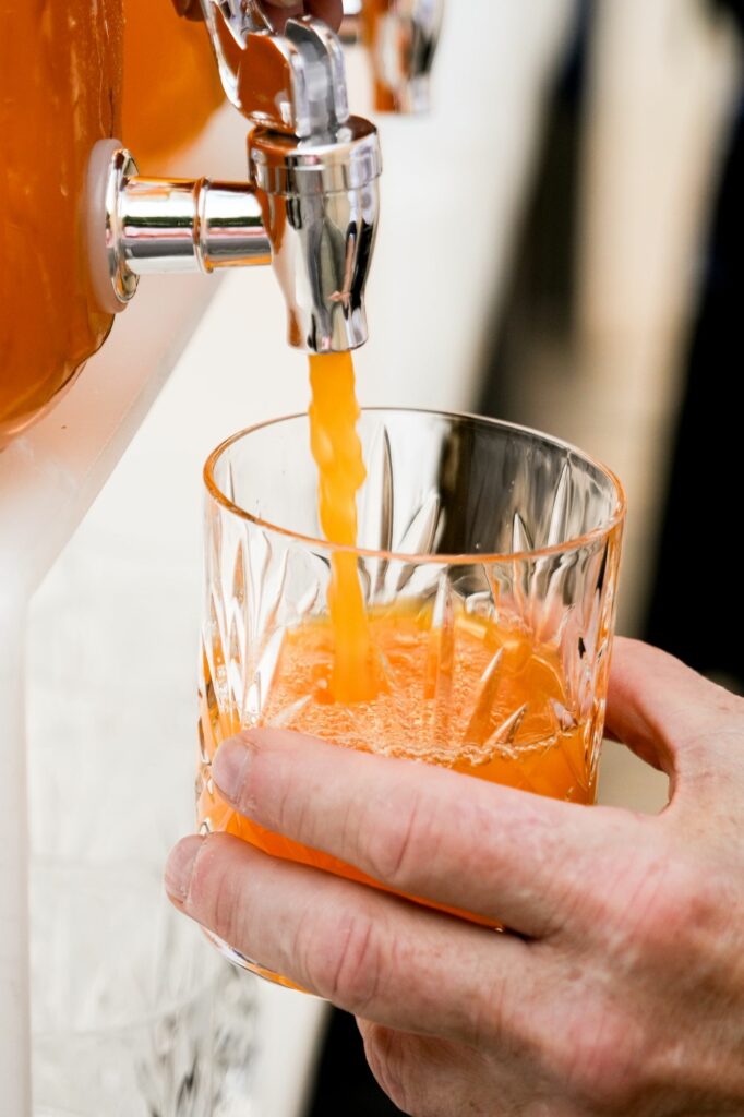 Jus d’orange versé d’une fontaine dans un verre en cristal