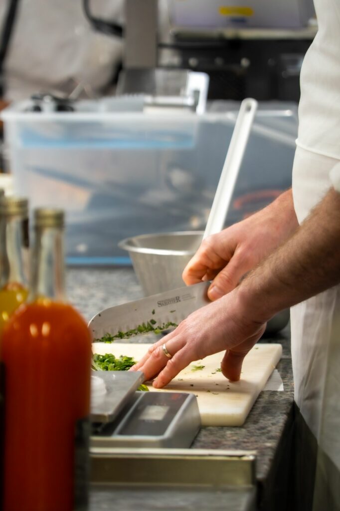 Chef ciselant des herbes sur une planche en cuisine