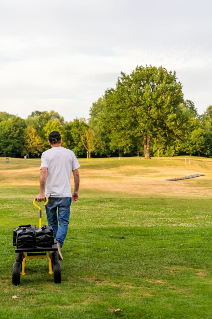 Technicien tirant un chariot de matériel sur le parcours de golf