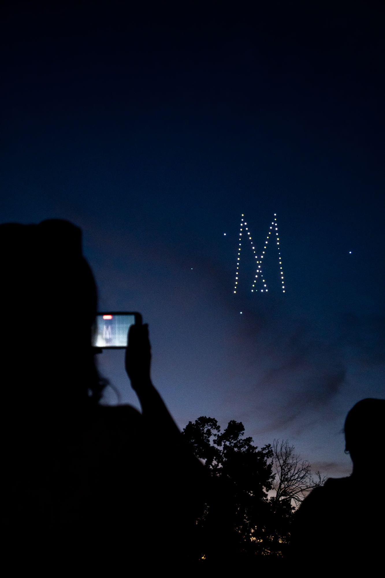 Drones dessinant une lettre dans le ciel, filmée par un invité