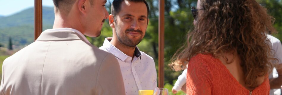 Invités discutant verre à la main au soleil