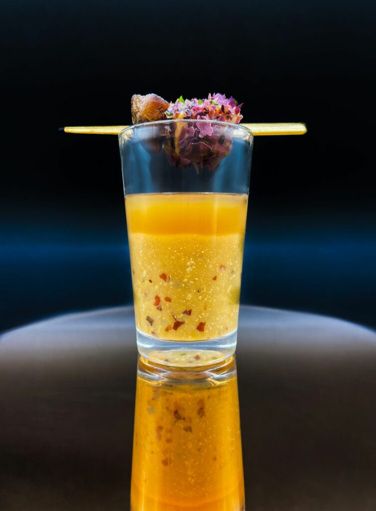 Verrine de soupe orangée surmontée d’une brochette fleurie