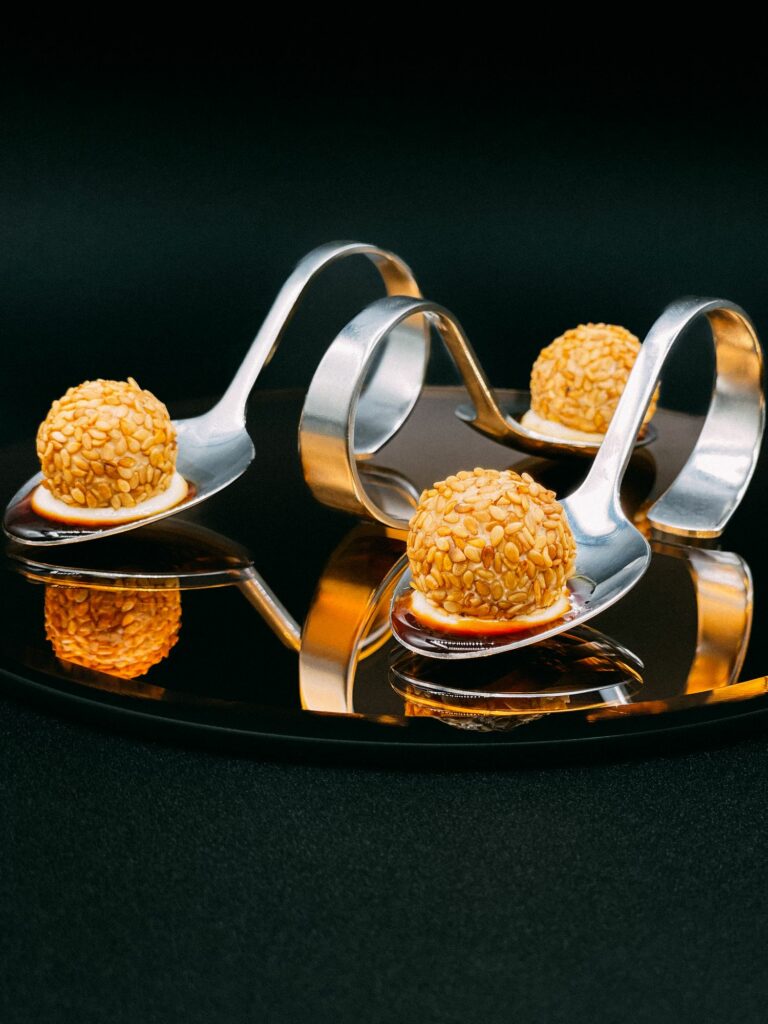 Bouchées panées dorées présentées sur cuillères en inox
