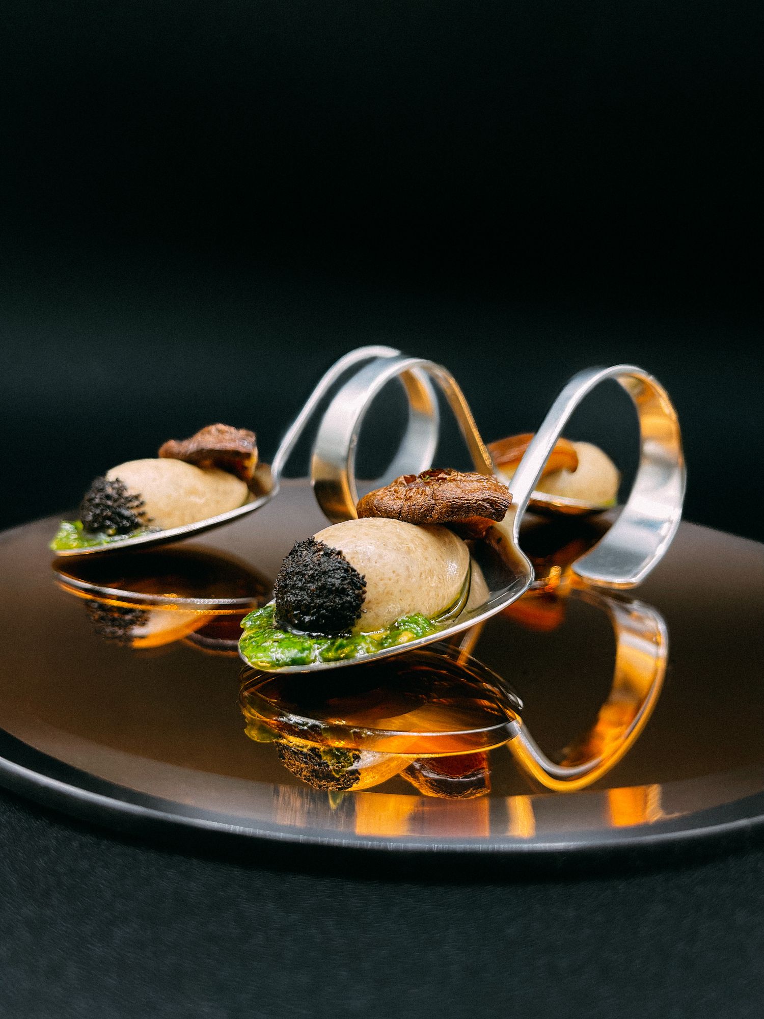 Cuillères apéritives garnies en reflet sur fond sombre