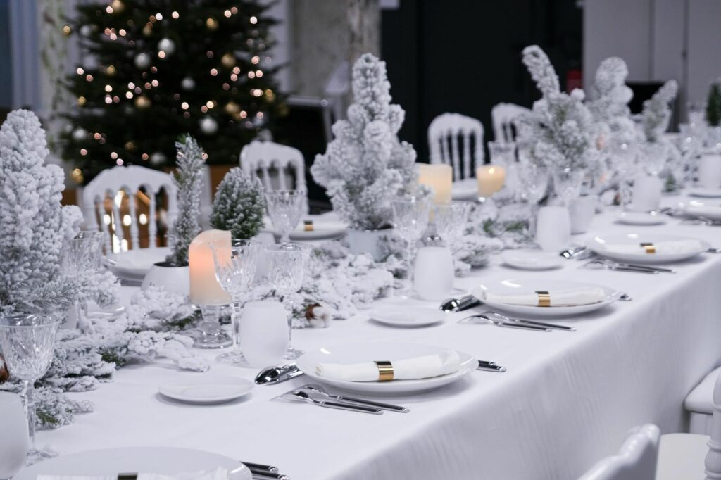 Longue table blanche de Noël avec sapins floqués et bougies