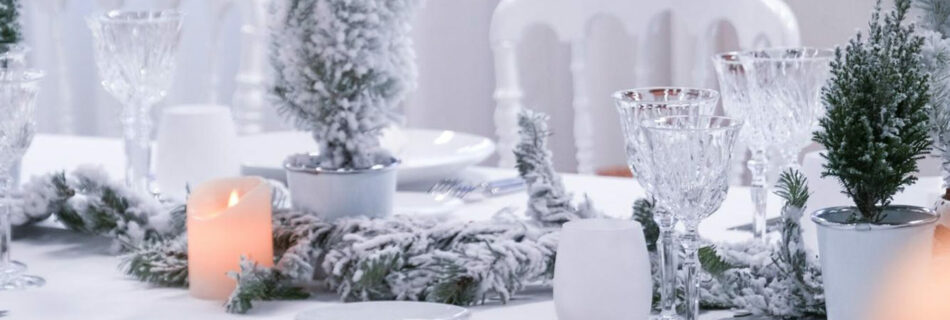 Assiette dressée sur la table de Noël blanche, sapins floqués en arrière-plan
