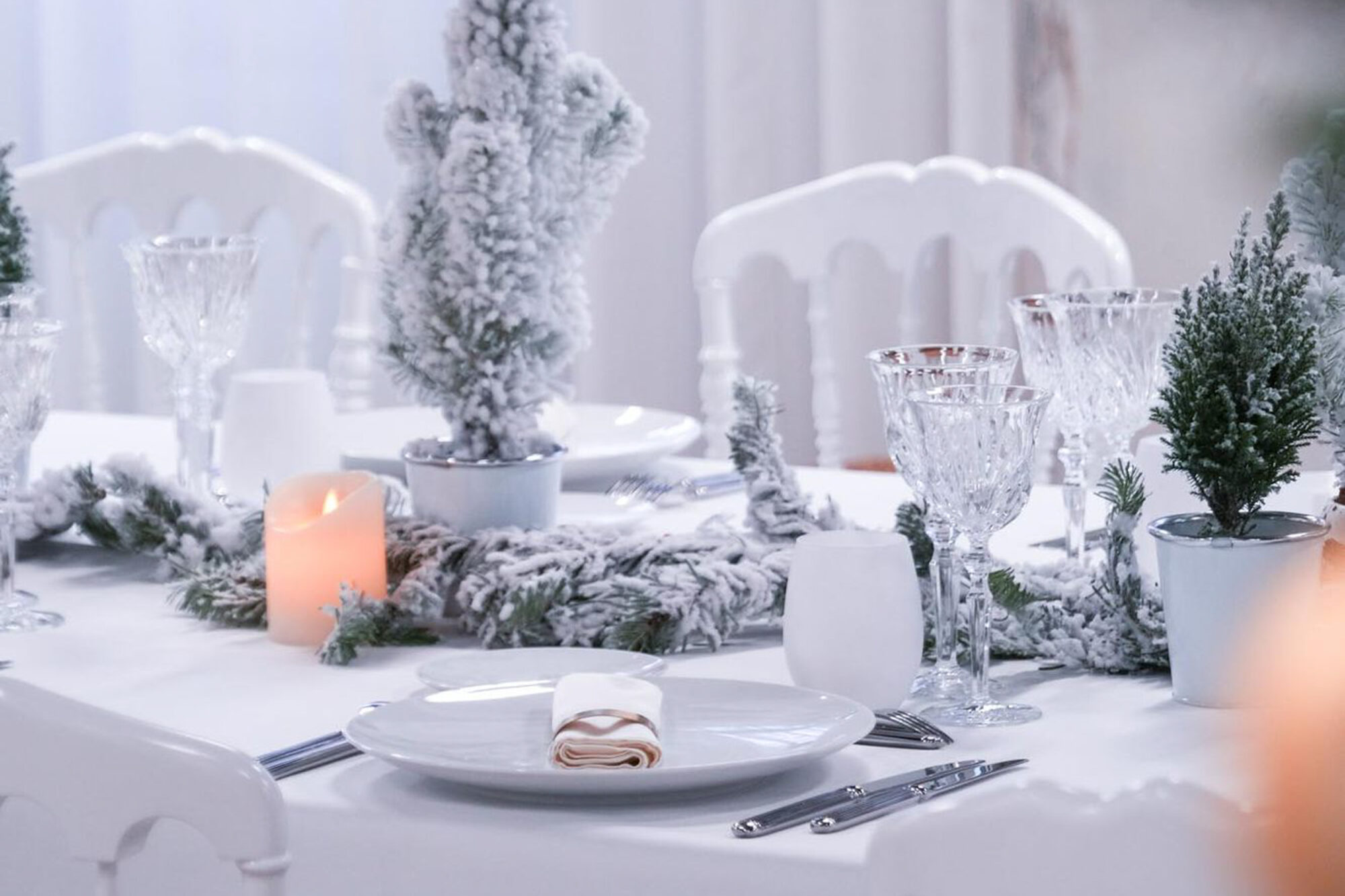Assiette dressée sur la table de Noël blanche, sapins floqués en arrière-plan