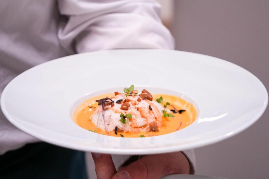 Assiette creuse avec un plat garni tenue par un serveur