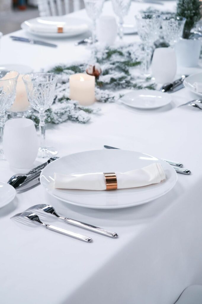 Couvert dressé avec serviette et rond doré sur nappe blanche